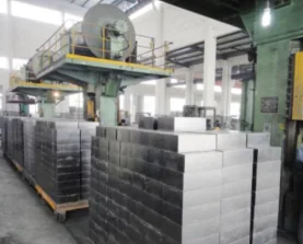 Brick-pressing shop with a large hydraulic press and rows of freshly pressed dark bricks stacked on pallets