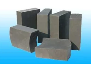 Group of dark grey magnesia-carbon bricks, including arched and straight shapes, on a light blue backdrop