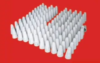 Batch of small tapered non-wetting precast parts arranged on a red background